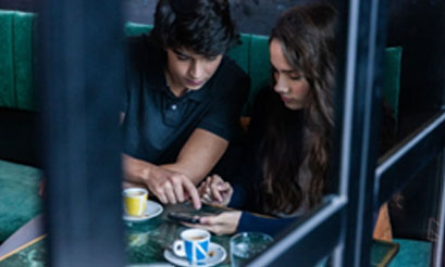 Dos jóvenes mirando el móvil en una cafetería