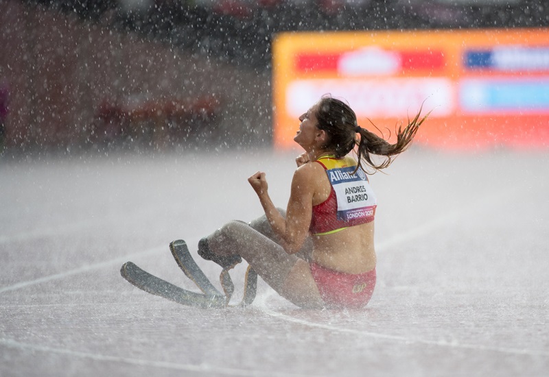Sara Andr&eacute;s celebrant sota la pluja la medalla de bronze asseguda a terra a la pista d'atletisme.