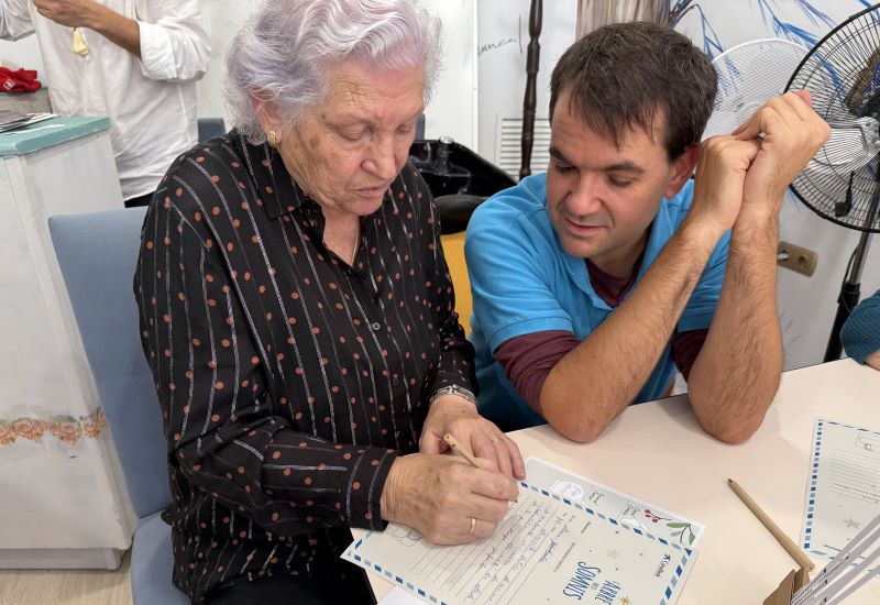 Un voluntari de CaixaBank ajuda una anciana a escriure la carta de L&rsquo;arbre dels somnis
