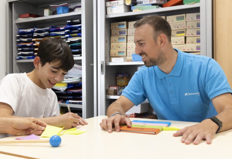 Un voluntari de CaixaBank participa en una activitat de foment de la lectura amb un adolescent.