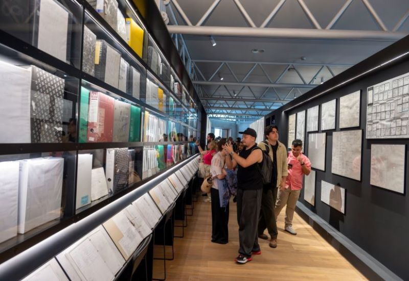 Persones recorren un passad&iacute;s amb documents i arxius exposats en vitrines.