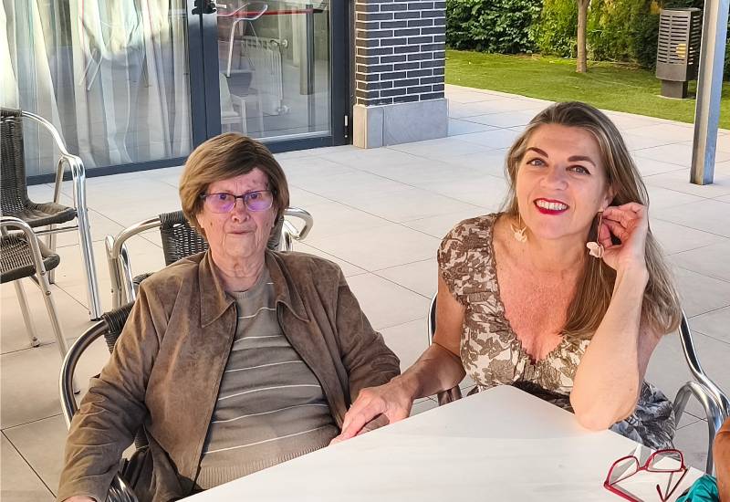 Una volunt&agrave;ria de CaixaBank, la Luc&iacute;a, al costat de la Lourdes, una persona gran que va con&egrave;ixer a trav&eacute;s del voluntariat corporatiu, posen davant d'una taula per a una foto