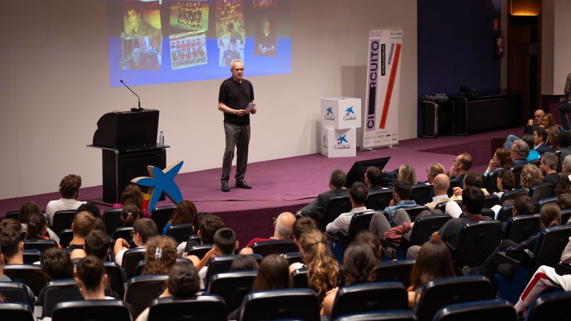 Més de 3.000 alumnes han escoltat Julio Alberto en les xerrades del Circuito Relife Persona a l’escenari d’un auditori fent una xerrada, amb pantalla de projecció al darrere i públic assegut escoltant, esdeveniment interior amb il·luminació càlida