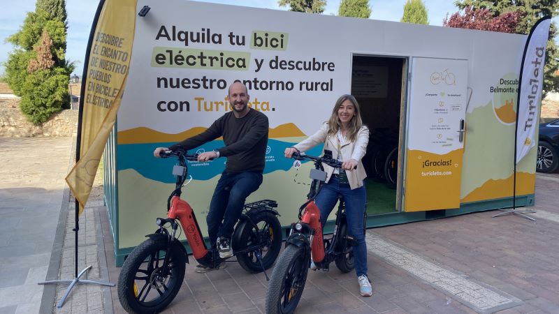 Dues persones sobre bicicletes el&egrave;ctriques davant del punt de lloguer de Turicleta, amb informaci&oacute; tur&iacute;stica i promoci&oacute; de l&rsquo;entorn rural.