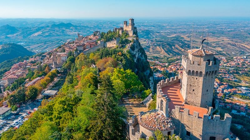 La superfície de San Marino ocupa 61 km² i acull uns 34.000 habitants Vista aèria de San Marino, ciutat situada sobre una muntanya, amb muralles, torres i edificacions envoltades d’un ampli paisatge natural