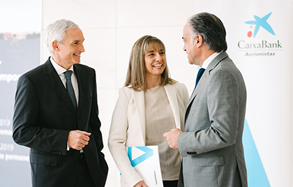 Dos hombres y una mujer elegantes conversando en una subcursal de CaixaBank