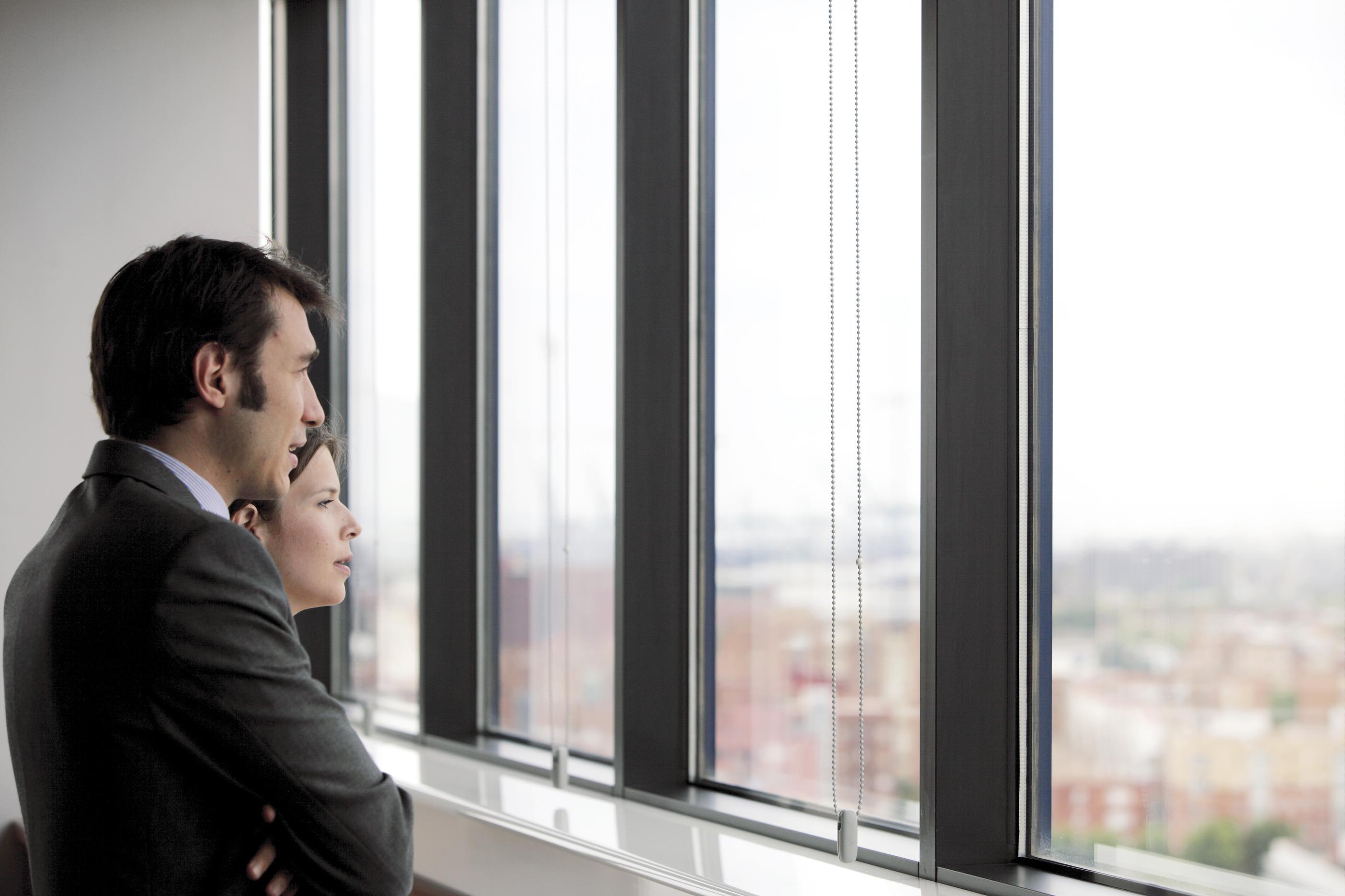 Hombre y mujer vestidos elegantes mirando desde la ventana