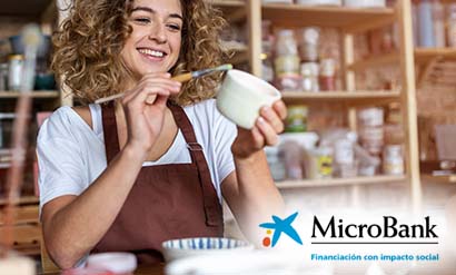 Mujer pintando una taza con el texto debajo de MicroBank, financiación con impacto social de CaixaBank