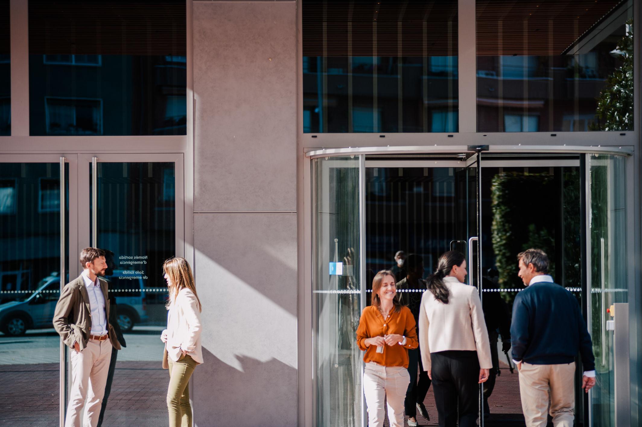 Dos grupos de personas en la puerta de un edificio hablando