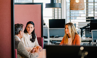 Un hombre y dos mujeres reunidos en una oficina 