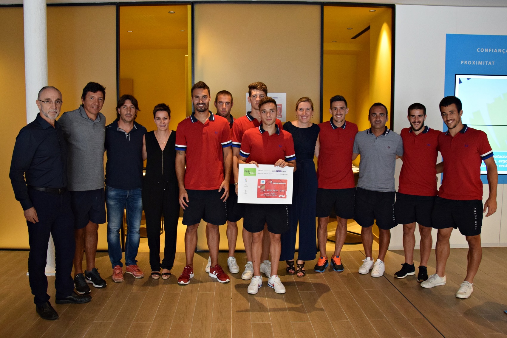 Jugadores del U.E. Olot y Montserrat Benítez, directora del Área de Negocio de CaixaBank en La Garrotxa durante el acto de entrega de las tarjetas financieras