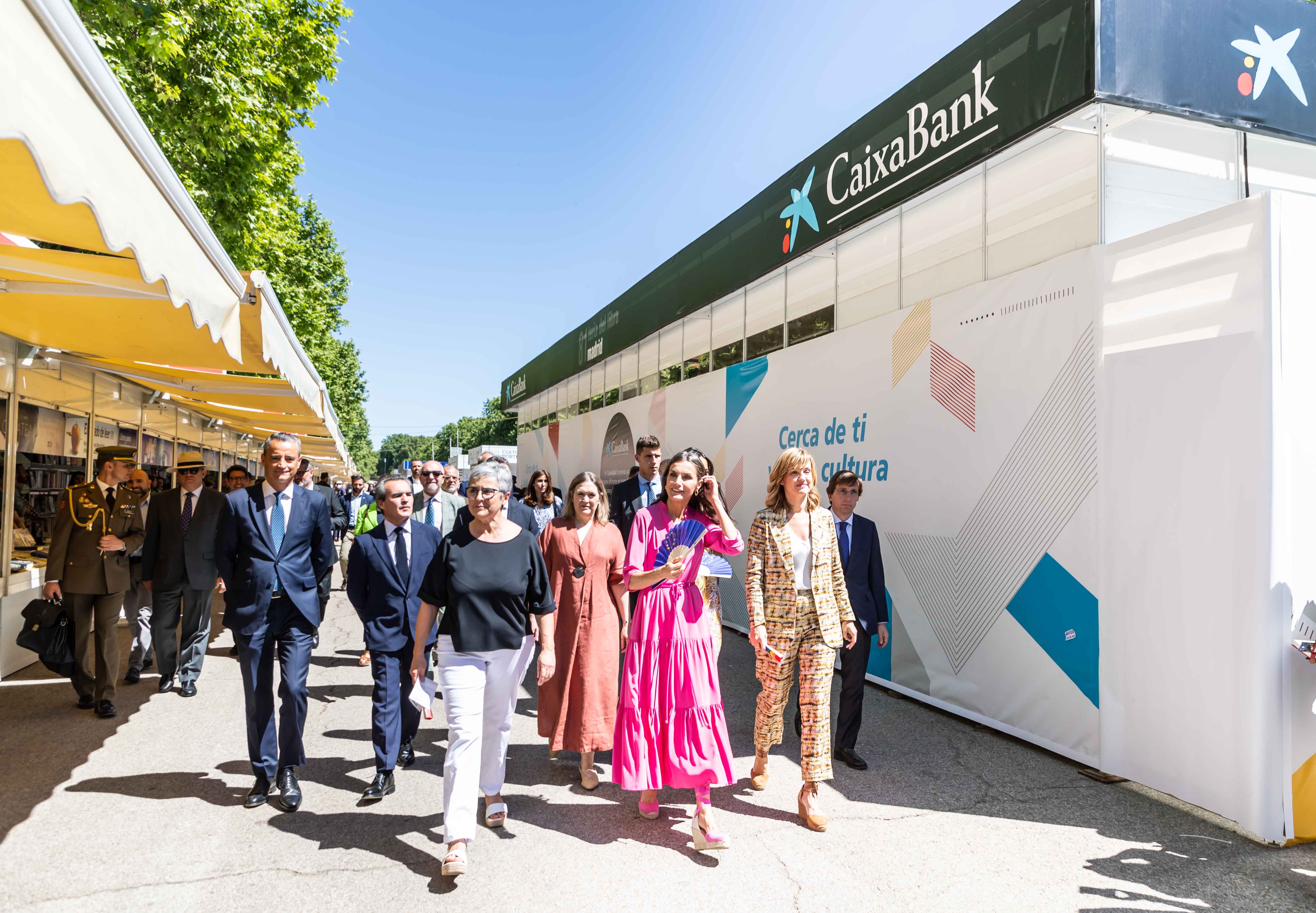 De izda. a dcha. Los directores territoriales Madrid Sur y Madrid Metropolitana de CaixaBank, Juan Luis Vidal y Rafael Herrador, en la comitiva inaugural de la Feria del Libro con la Reina Letizia, la directora de la Feria del Libro, la consejera de Cultura, la ministra de Educación, y el alcalde de Madrid pasando por el ‘Pabellón CaixaBank de Actividades Culturales’.