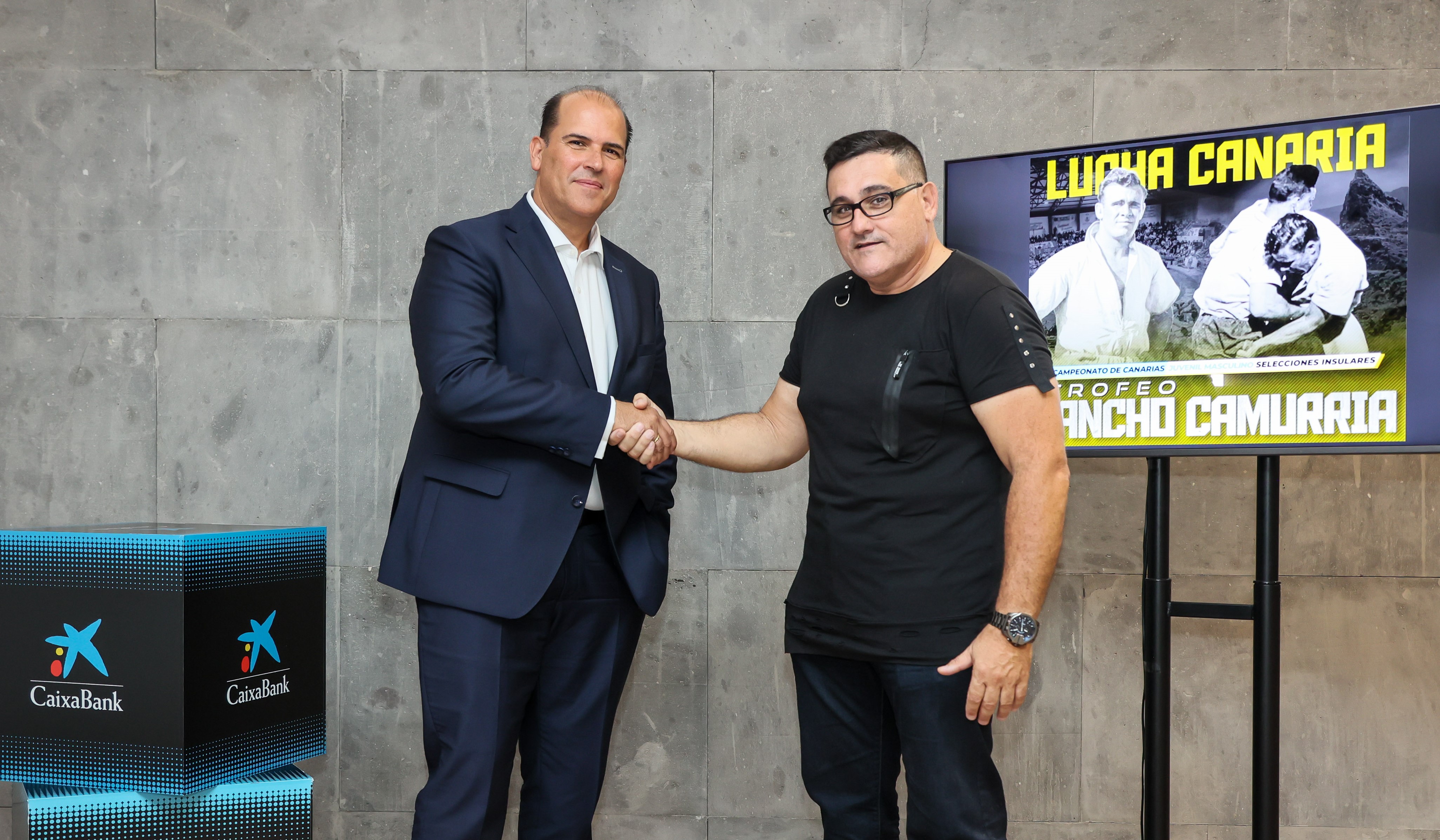 Esta nueva alianza ha sido presentada por el director territorial de CaixaBank en Canarias, Manuel Afonso, y por el presidente de la Federación Canaria de Lucha, José Antonio Caballero. 