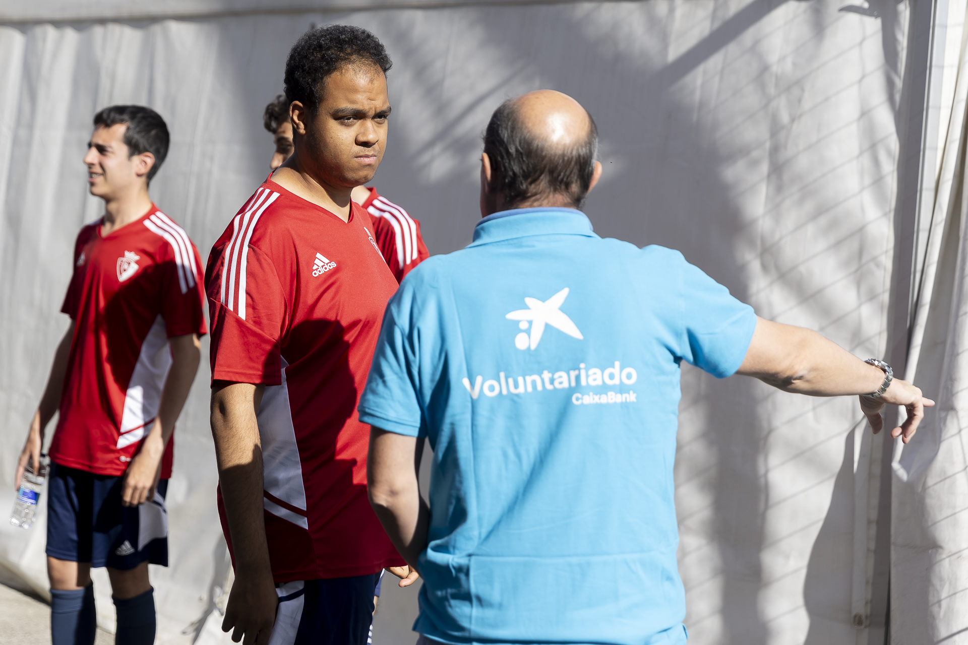 Un jugador del C.A. Osasuna Genuine atiende las explicaciones de un voluntario de CaixaBank