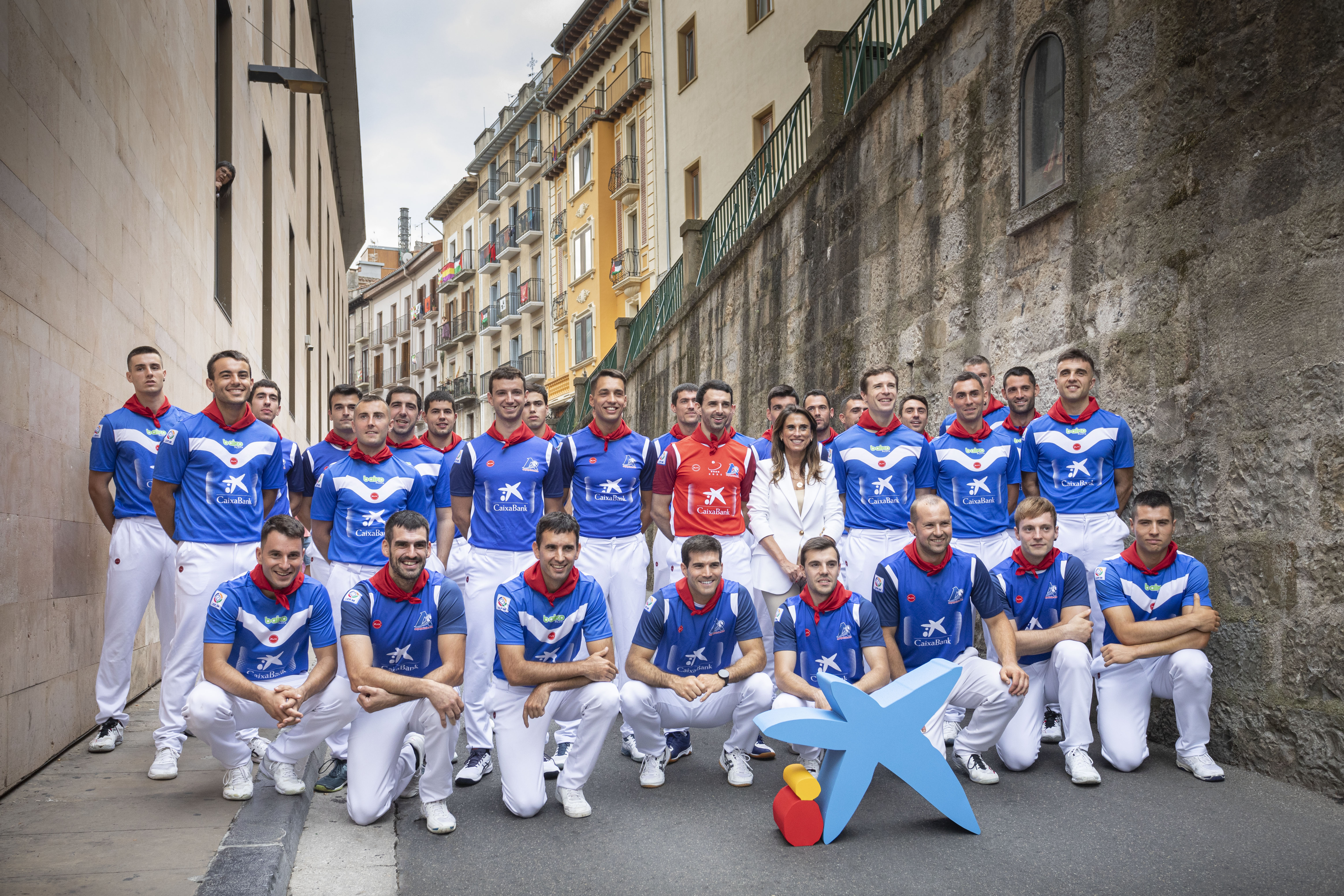 Isabel Moreno, directora territorial Ebro de CaixaBank, junto con los pelotaris en la cuesta de Santo Domingo, delante de la hornacina con San Fermín, lugar donde todas las mañanas entre el 7 y 14 de julio, antes de comenzar el encierro, se canta la tradicional canción al santo.