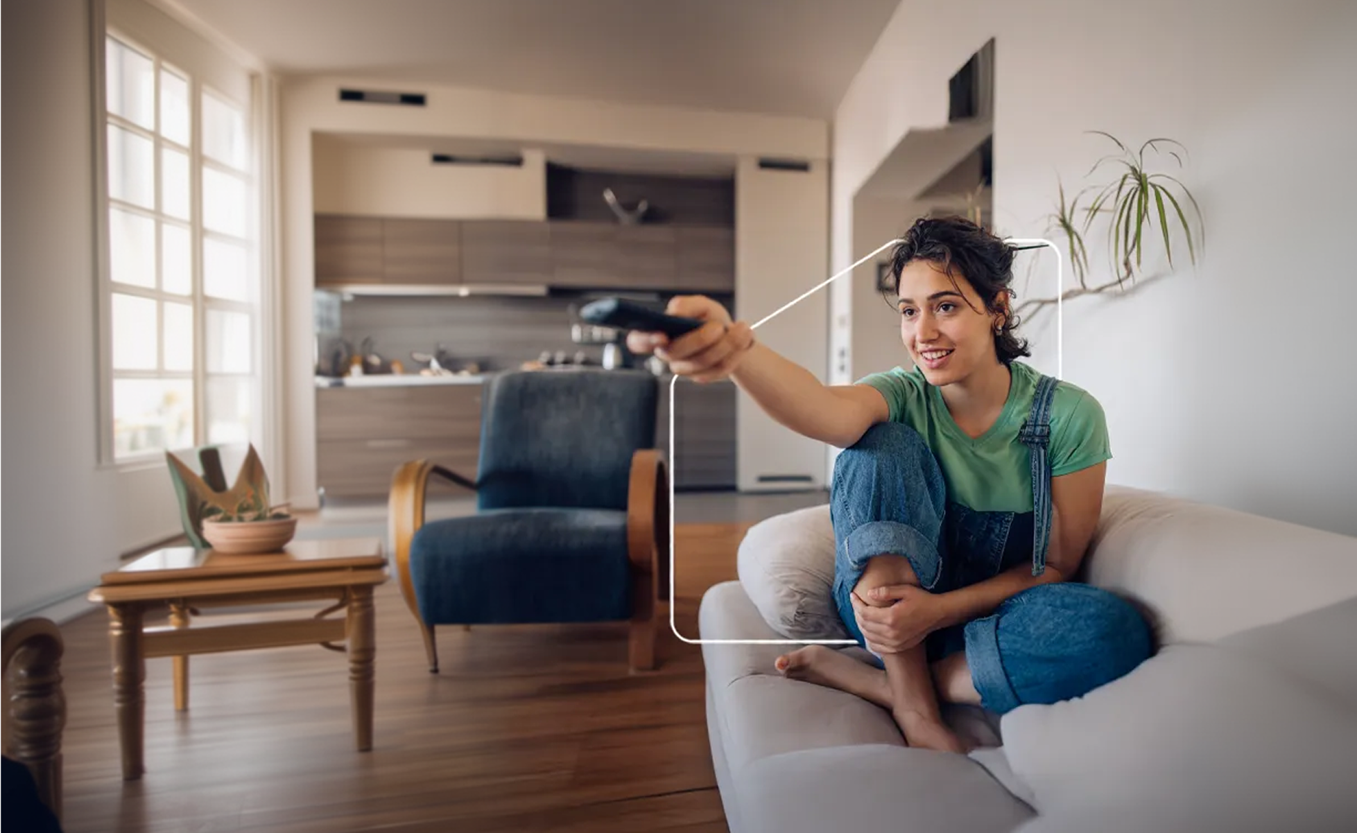 Una mujer sentada en su sofá cambia de canal de televisión desde el salón de su casa.
