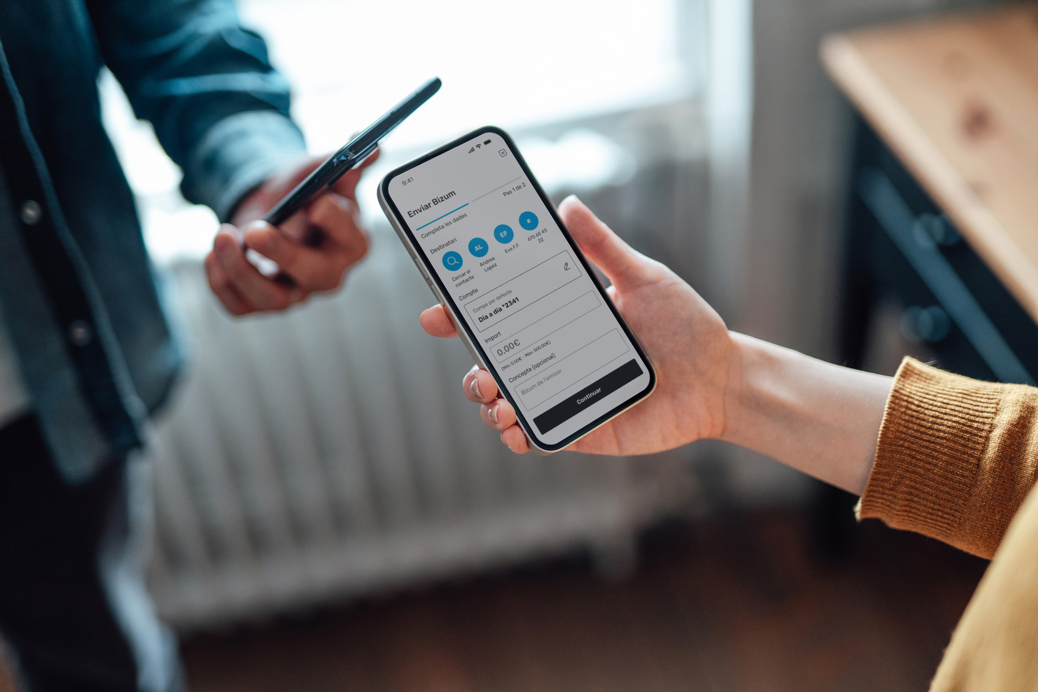 Two people make an instant money transfer through Bizum.
