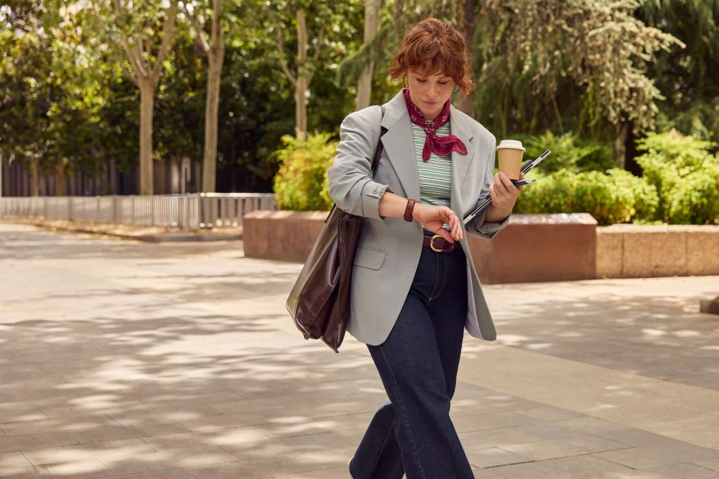 Un home camina per un parc amb un telèfon intel·ligent a la mà