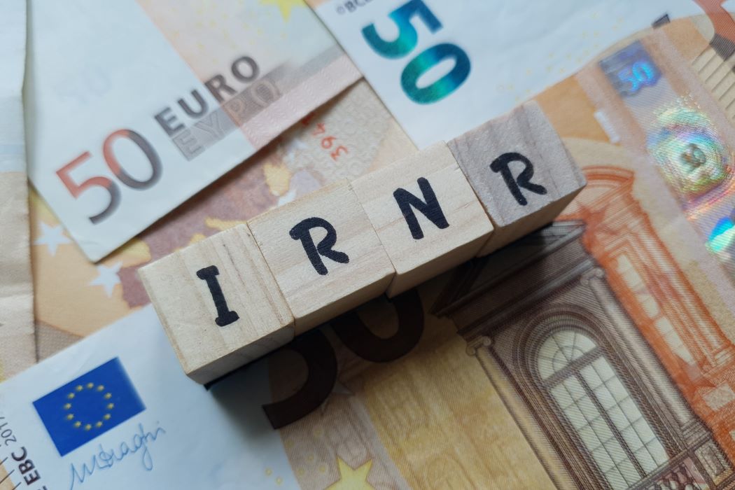 Acrónimo de Impuesto de la Renta de no Residentes, IRNR, en cubos de madera sobre billetes de 50 euros