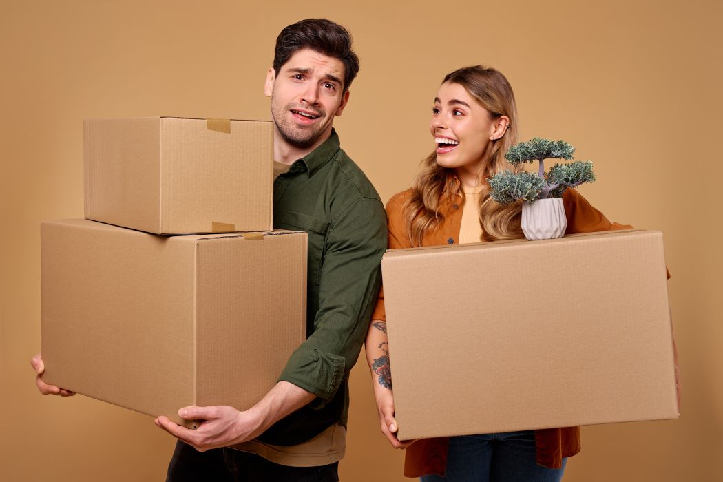 Pareja joven y alegre sujeta unas cajas de cartón tras una mudanza
