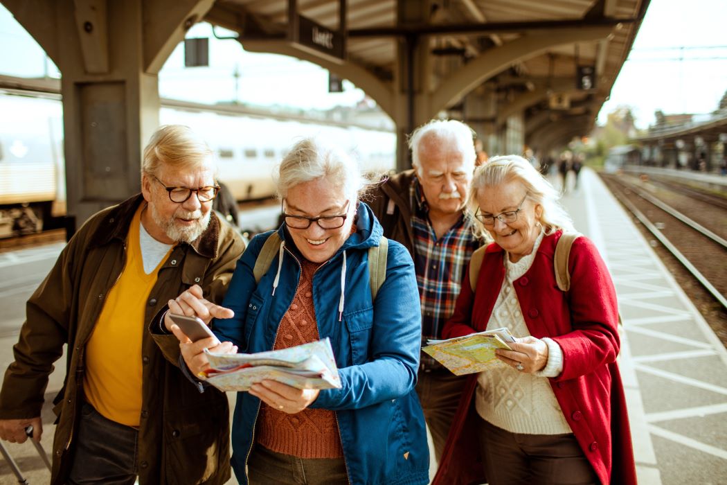 Grupo de viajeros mayores consultando un mapa en un andén de tren