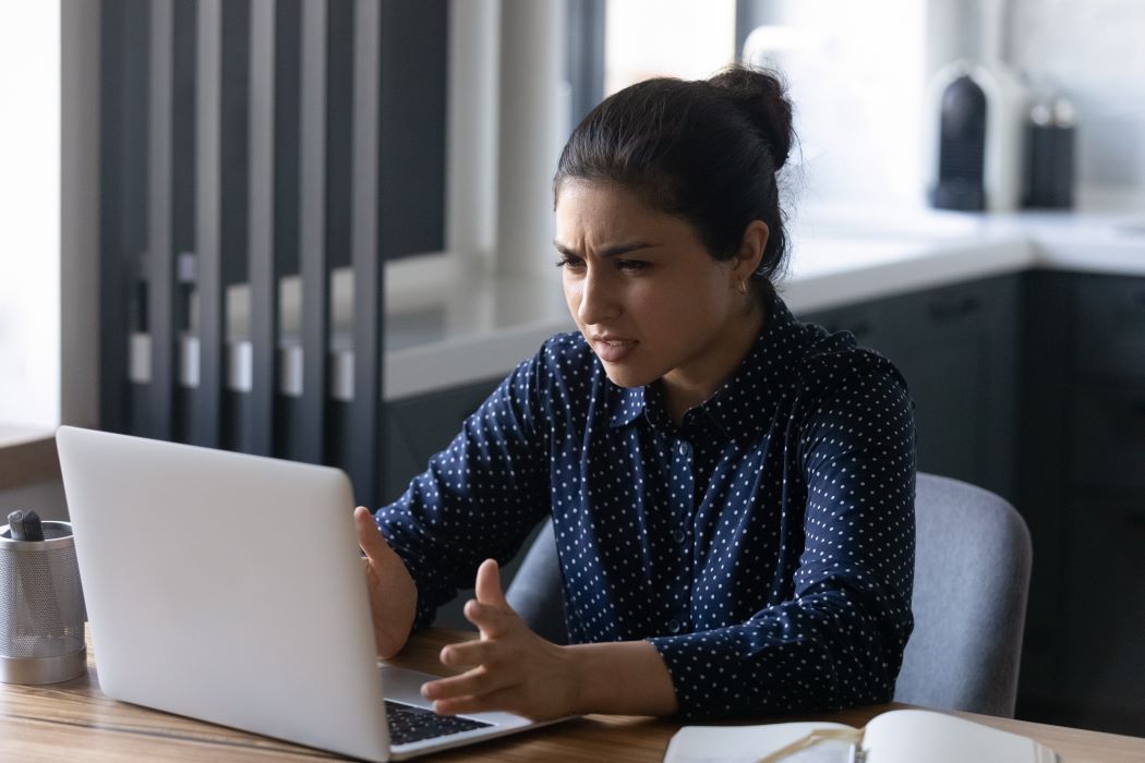 Una mujer se muestra sorprendida frente a un ordenador portátil