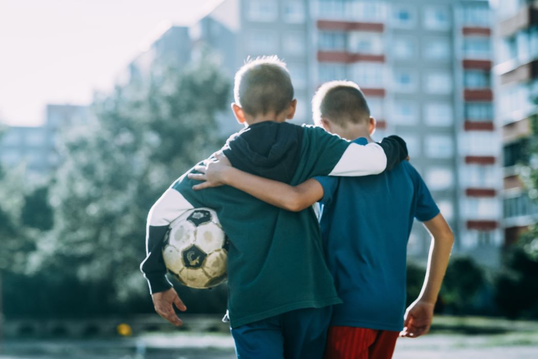 Dos niños, amigos, entrenan al fútbol mientras se relacionan y disfrutan.