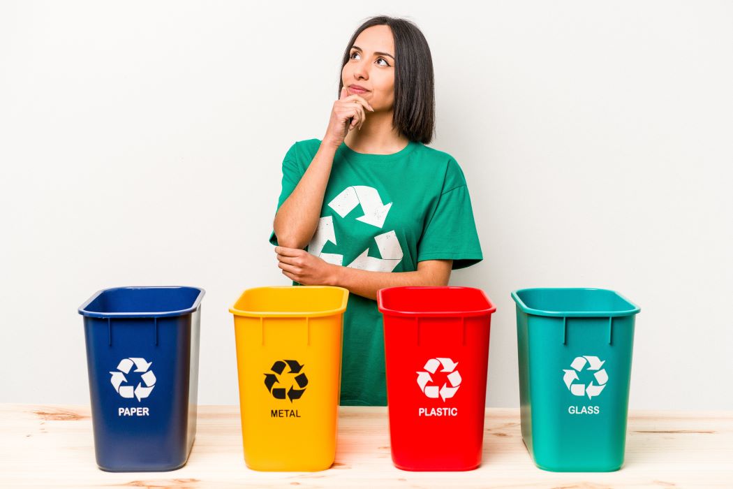 Persona recicla en su casa con cuatro cubos de basura diferentes.