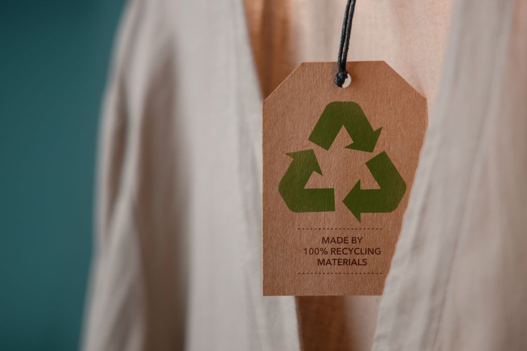 Etiqueta de cartón con símbolo de reciclaje en prenda sostenible