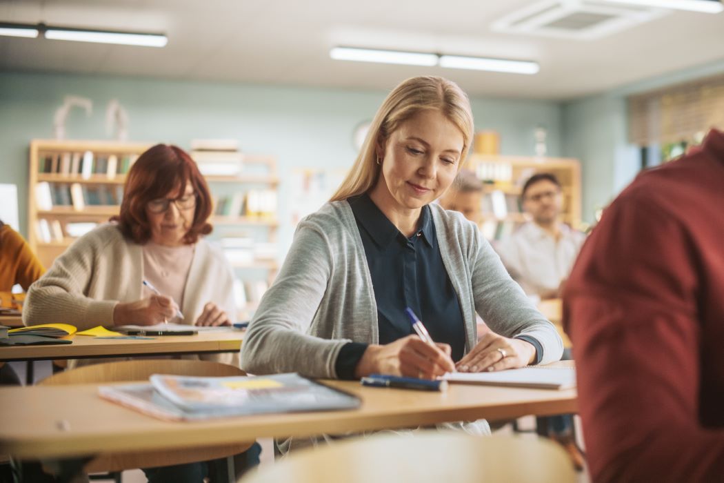 Personas adultas escribiendo en un aula durante una actividad formativa