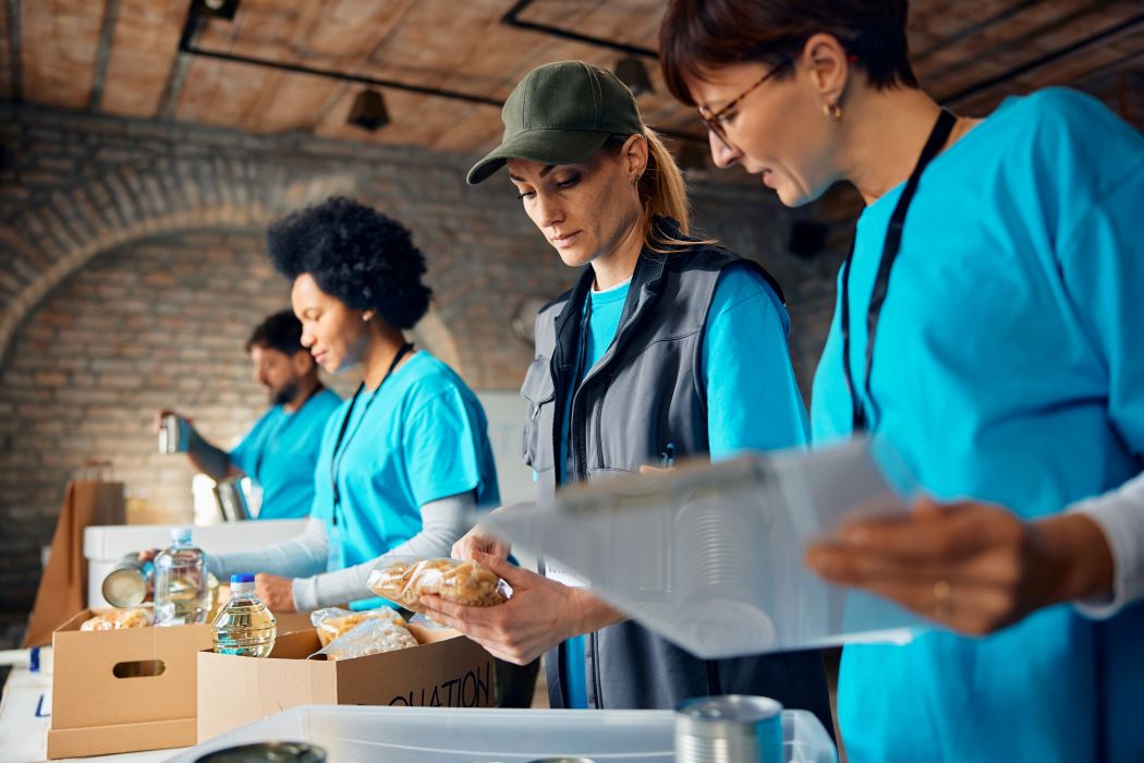 Voluntarios organizando alimentos y productos básicos en una mesa durante una jornada de reparto solidario