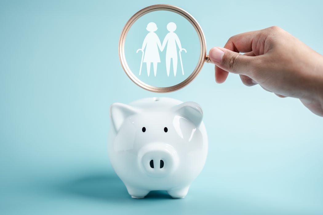 Guardiola en forma de porc sobre fons blau i una mà sostenint una lupa que mostra la icona d'una família