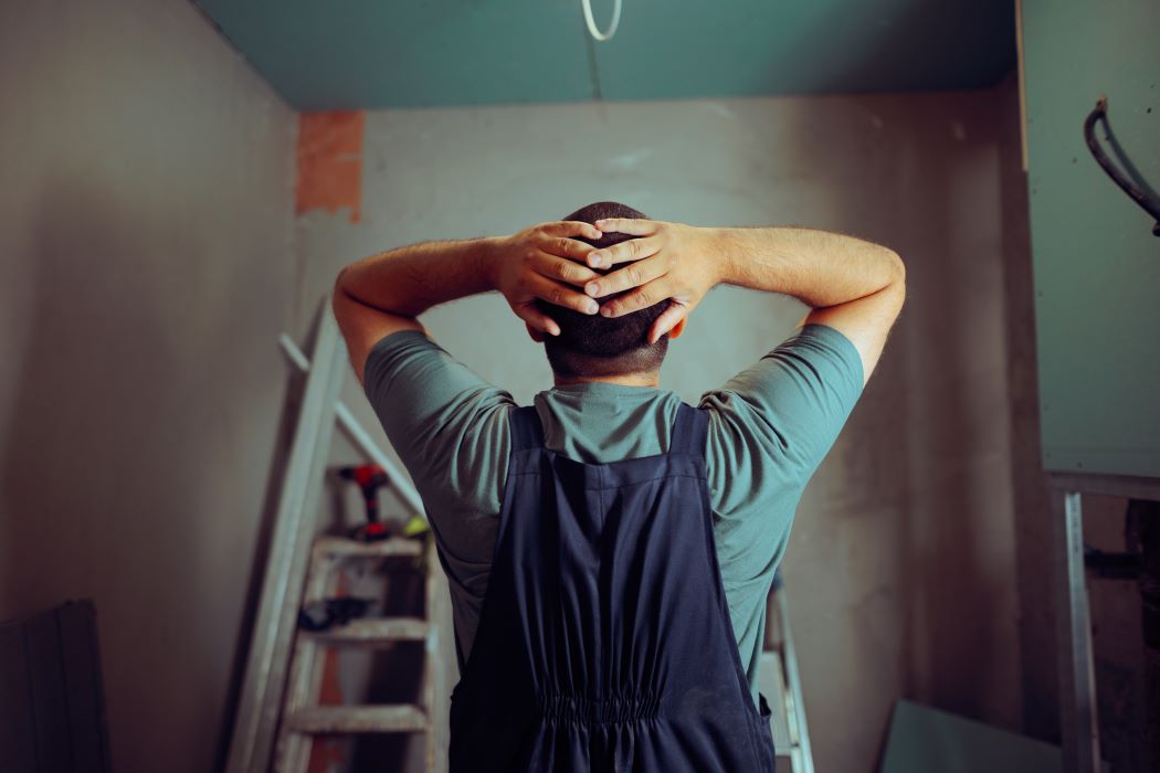Un hombre en una vivienda en reforma se lleva las manos a la cabeza al observar una obra mal planificada