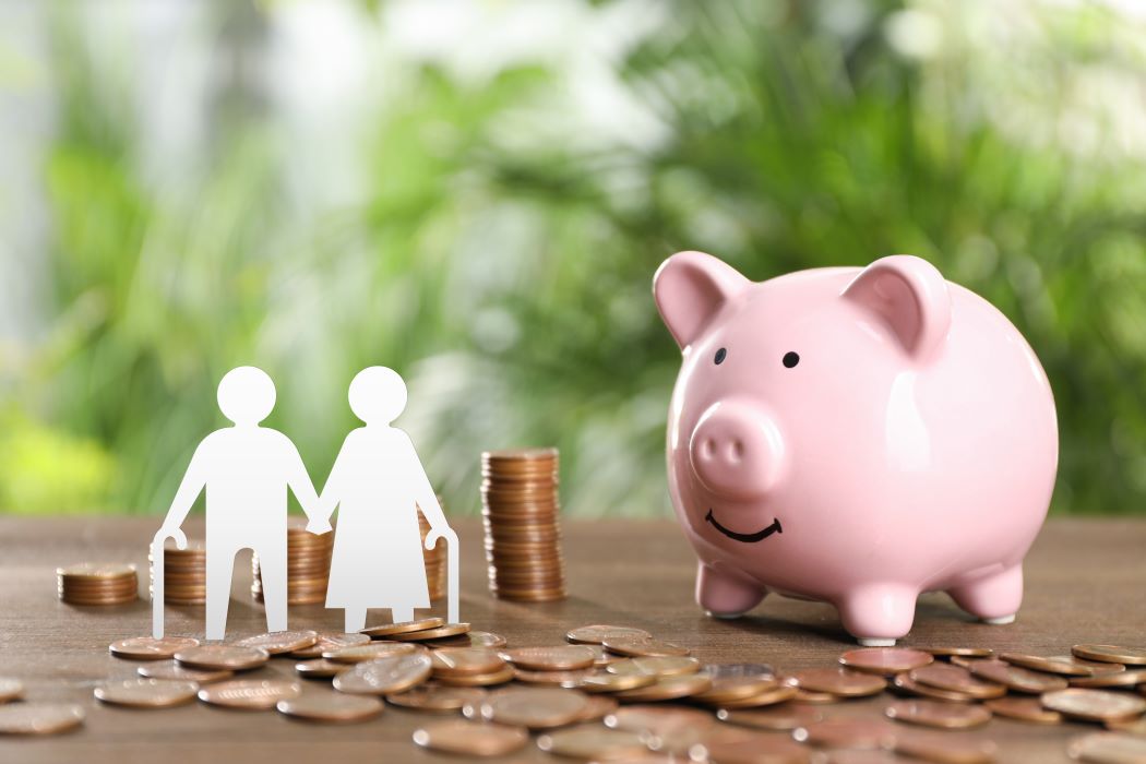 Guardiola en forma de porc al costat de monedes i siluetes d'una parella de persones grans