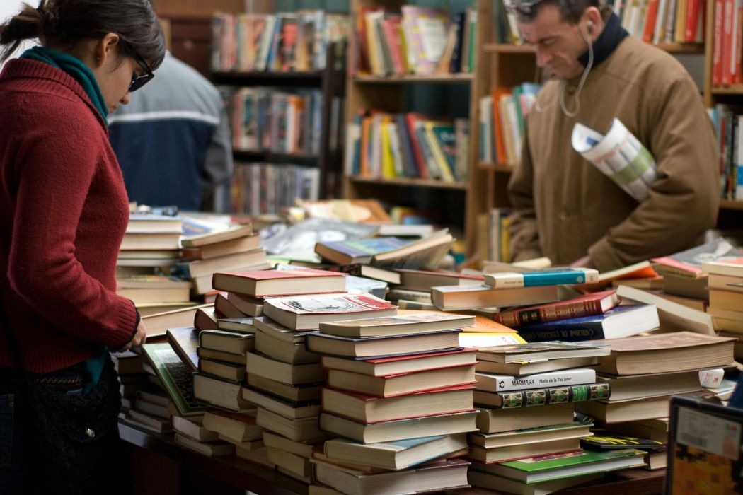 Imagen de varias personas mirando libros alrededor de una mesa de mostrador en una librería