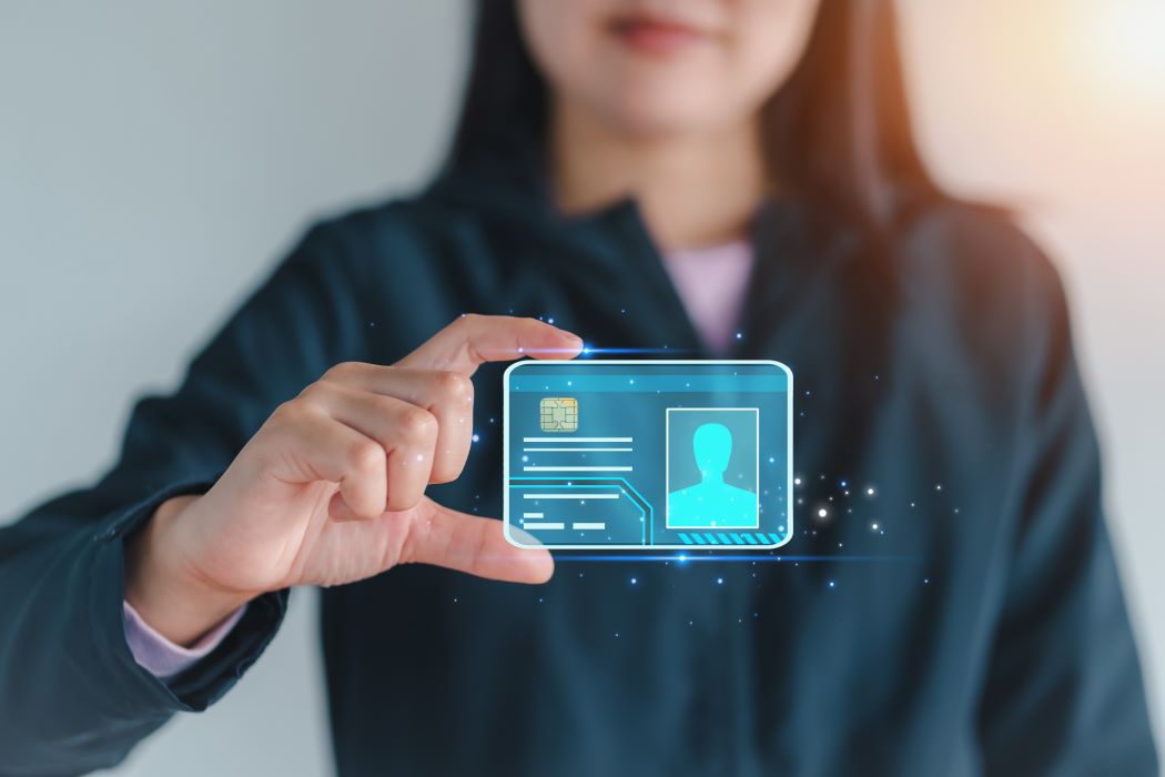 Una persona sostiene una tarjeta digital con chip y datos de identificación, representada como un holograma frente a un fondo desenfocado.