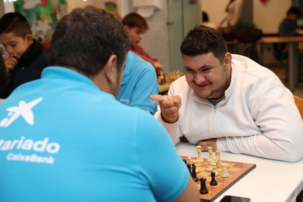 Alberto Jiménez, voluntario de CaixaBank, frente a un tablero de ajedrez con uno de los niños con los que juega en el Programa Paula Montal