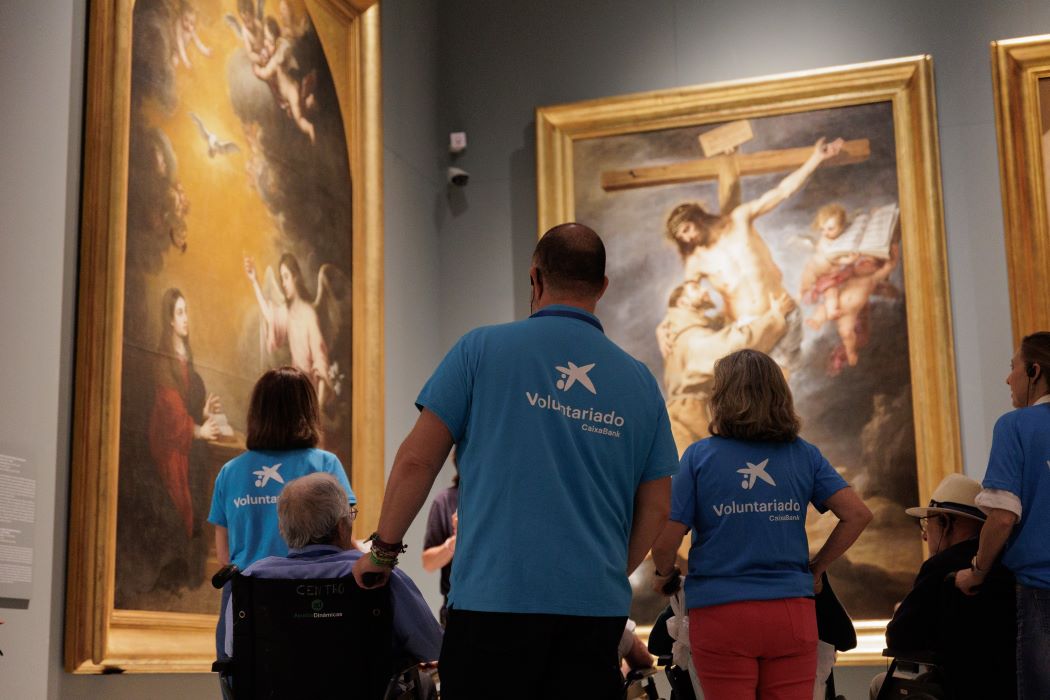 Un grupo de personas mayores disfrutan de una visita al museo acompañados de los voluntarios de CaixaBank en el día de los museos