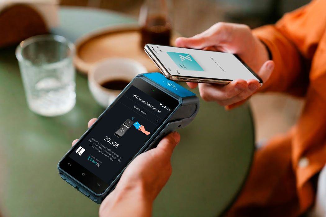 Pagament sense contacte amb mòbil en terminal datàfon per 20,50 € sobre taula amb begudes, escena de comerç digital quotidià