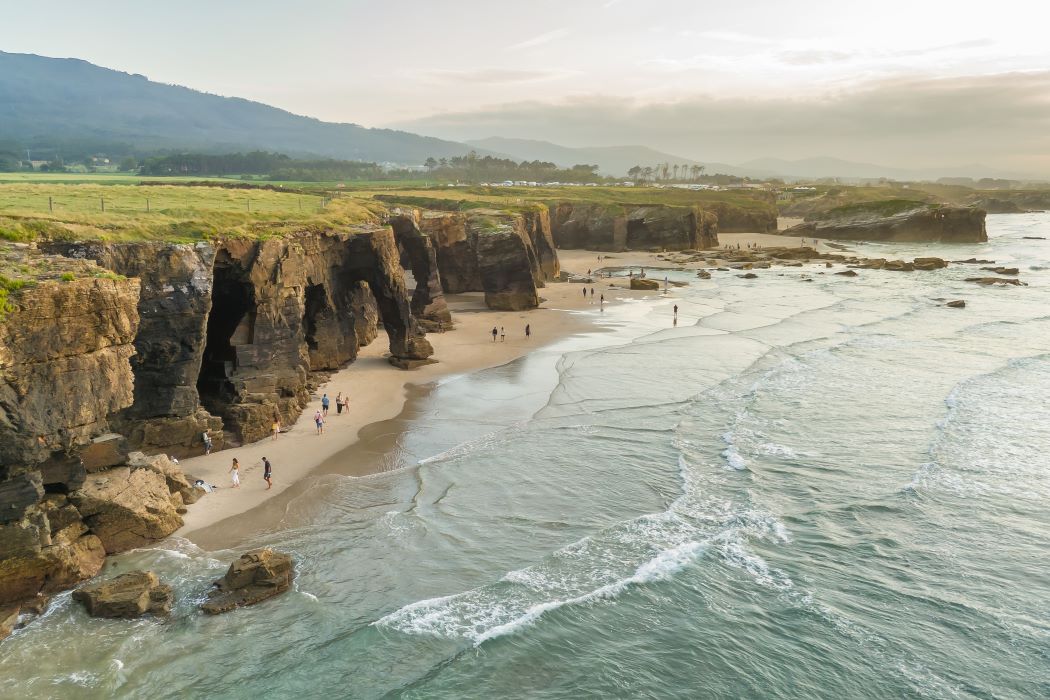 La platja de les Catedrals, a Lugo, en una vista aèria que la mostra en un dia ennuvolat amb un grapat de persones passejant per la sorra