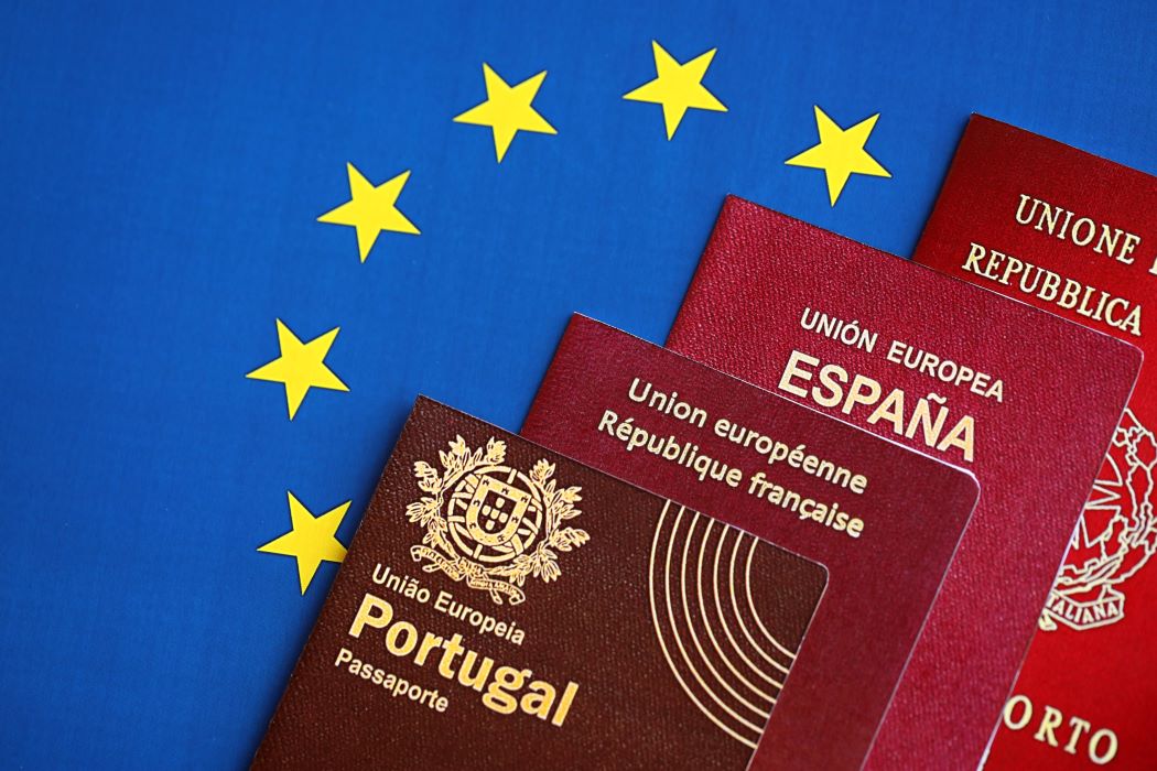 Quatre passaports, de Portugal, França, Espanya i Itàlia, sobre una bandera de la Unió Europea