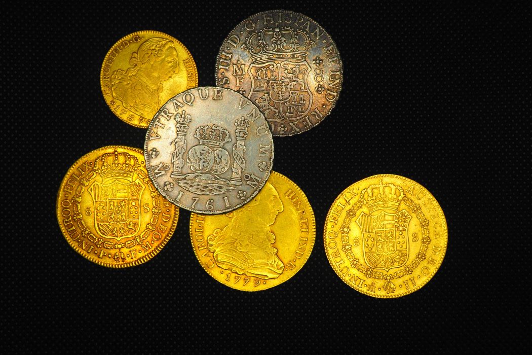 Conjunt de monedes històriques espanyoles d’or i plata dels segles XVIII i XIX, amb escuts i retrats gravats, sobre fons negre