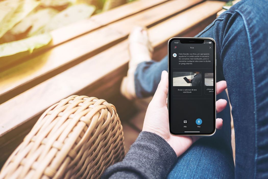 Una persona consulta la app móvil de su banco sentada en un sofá.