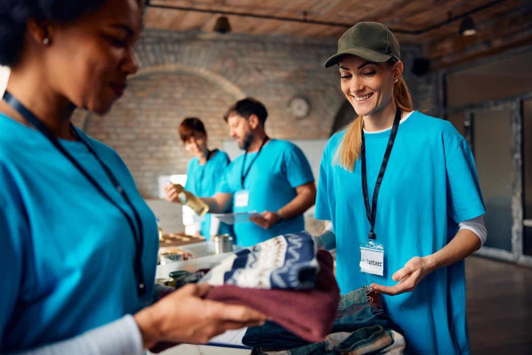 Personas voluntarias clasifican y entregan ropa y artículos donados en un centro comunitario durante una actividad de apoyo social