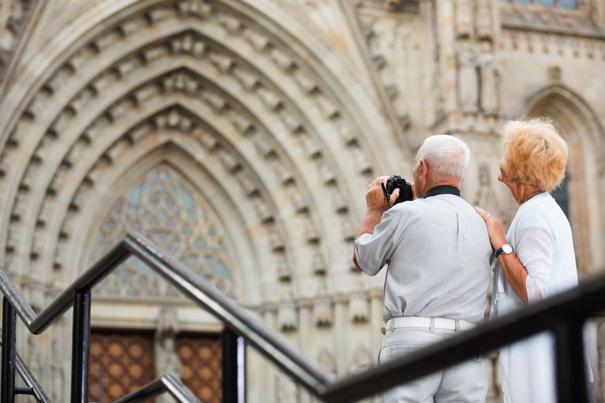 Una pareja de turistas sénior disfruta haciendo fotos delante de una catedral