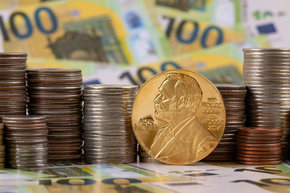 Moneda del Premi Nobel davant de piles de monedes d'euro i bitllets, símbol d'economia, recerca i reconeixement acadèmic