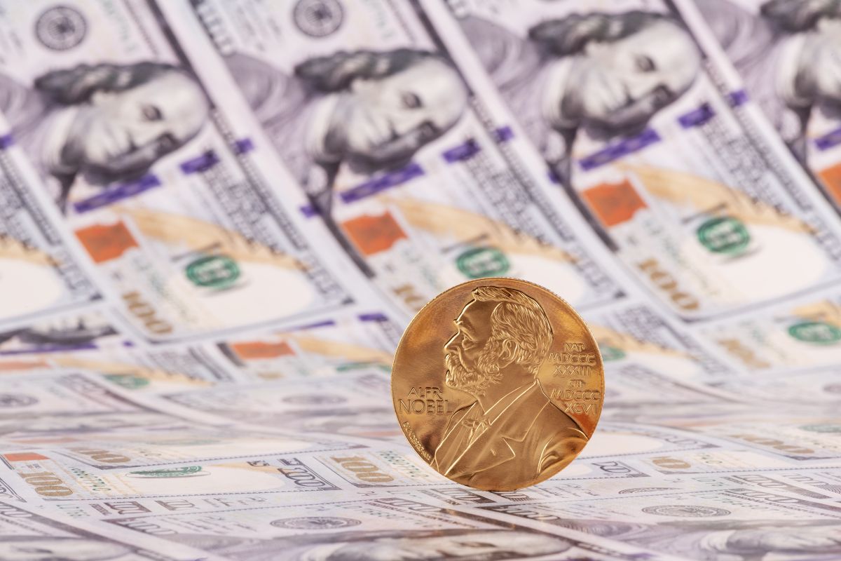 Medalla del Premio Nobel en primer plano sobre billetes de cien dólares estadounidenses, simbolizando reconocimiento, prestigio y dotación económica de los galardones.