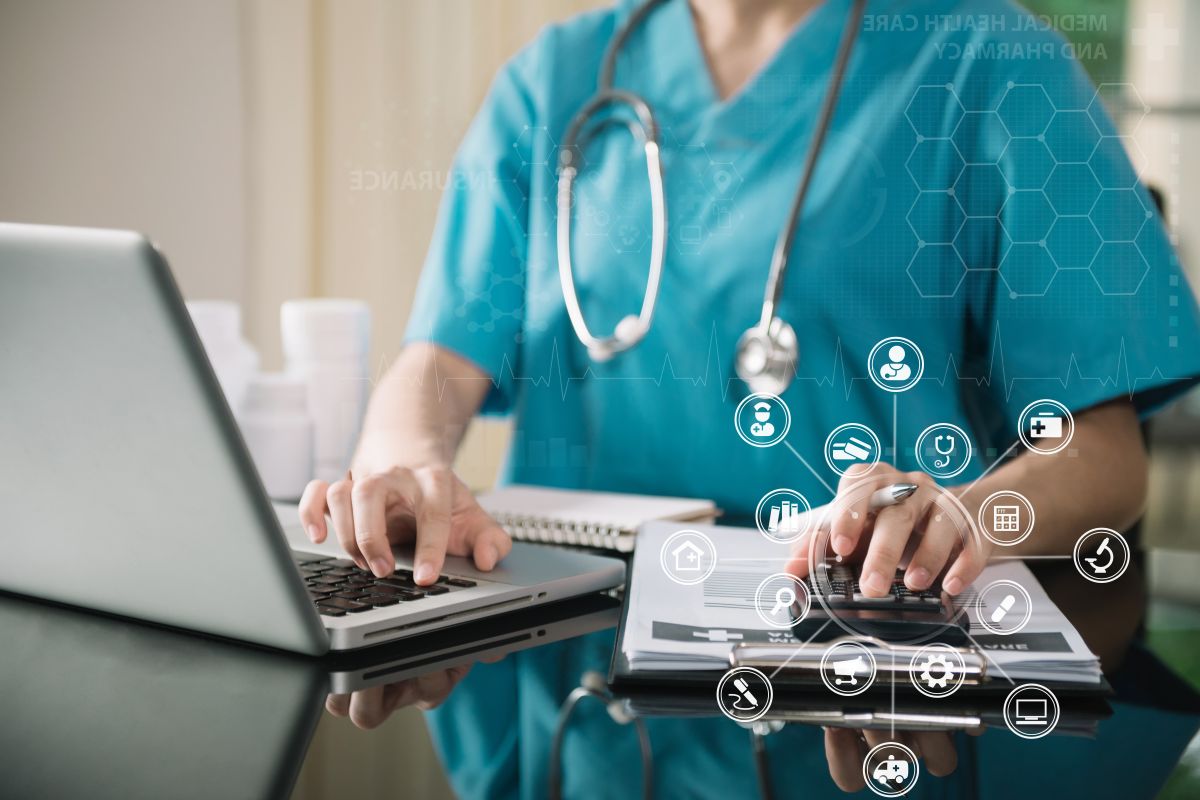 Profesional sanitario utilizando un ordenador portátil y una calculadora sobre documentación médica, con iconos digitales relacionados con la gestión de la salud.