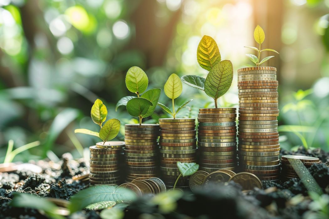 Pilas de monedas en crecimiento con pequeñas plantas verdes brotando encima, simbolizando inversión sostenible y rentabilidad financiera en un entorno natural luminoso