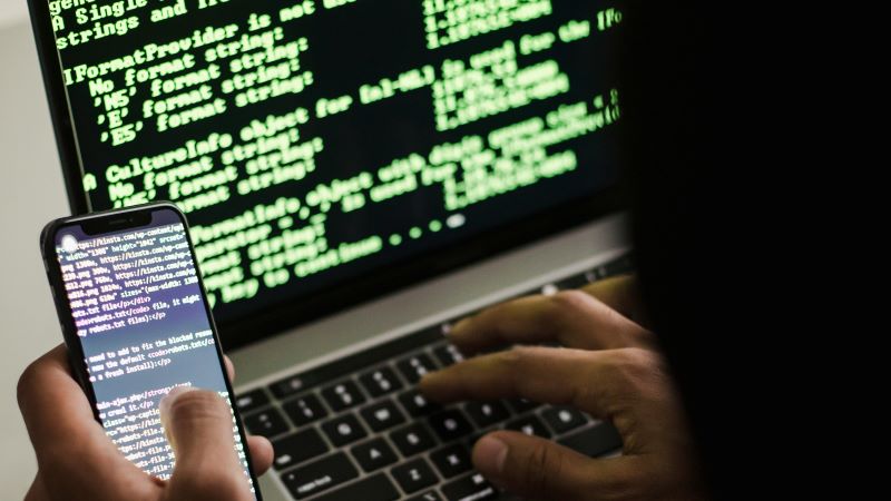 Conoce las tácticas de los estafadores para proteger tu dinero en Internet n hacker intenta manipular un código a través de un teléfono móvil y un ordenador